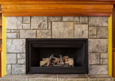 Black fireplace insert with stone surround and wood mantel