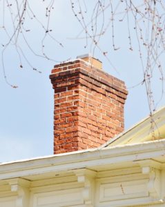view of masonry chimney between dangling branches