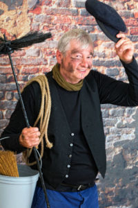 A Chimney Sweep Holing A Brush And A Hat With A Bucket And A Vest Smiling